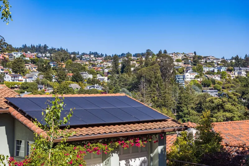 Suburban home with solar panels on the roof, surrounded by greenery